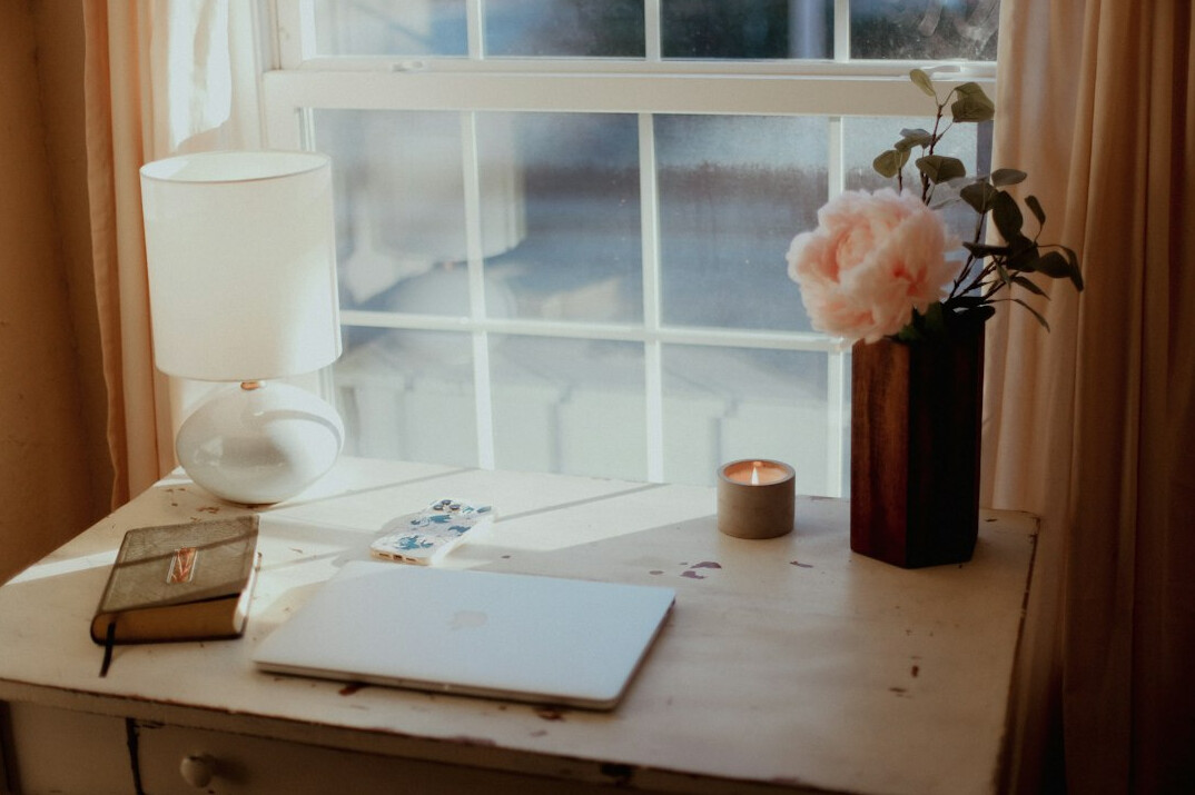 Open notebook and pen on a wooden desk with laptop